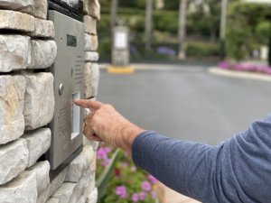 A man enters a code or keycode on panel to enter a gated neighborhood community