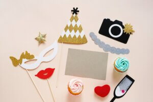 Cute party props and cake with blank card on yellow background. Birthday, wedding party celebration